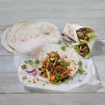 Tacobröd med kött grönskaer örter och andra färgsprakande tillbehör